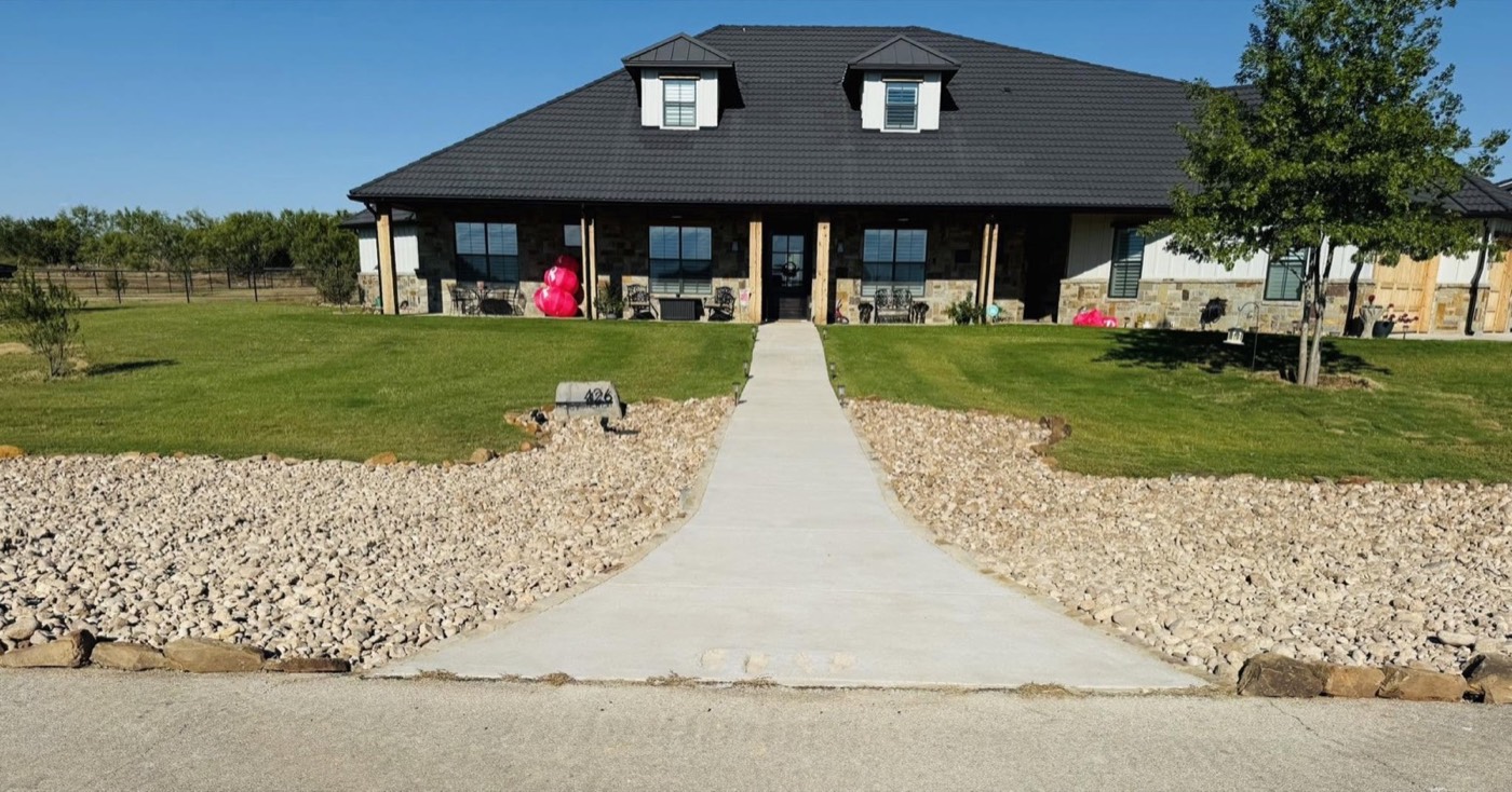 Completed driveway approach with stone borders and landscape beds