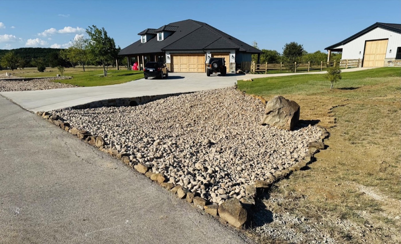 Large stone-edged landscape area beside a driveway