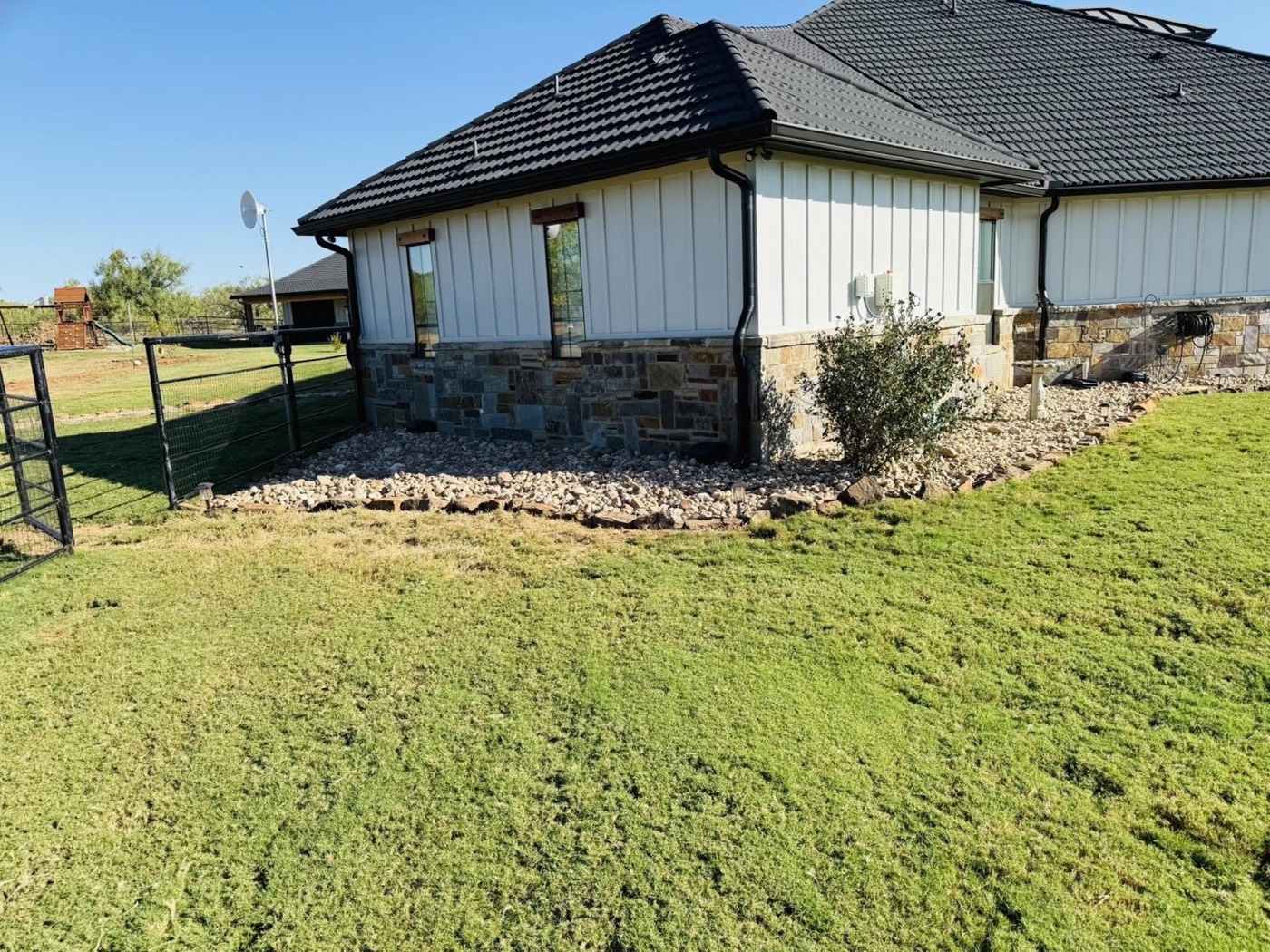 Side yard with lawn, rock beds, and stone borders