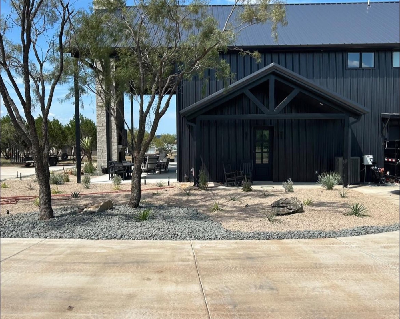 After: planted landscape with decorative rock and a green lawn beside a home