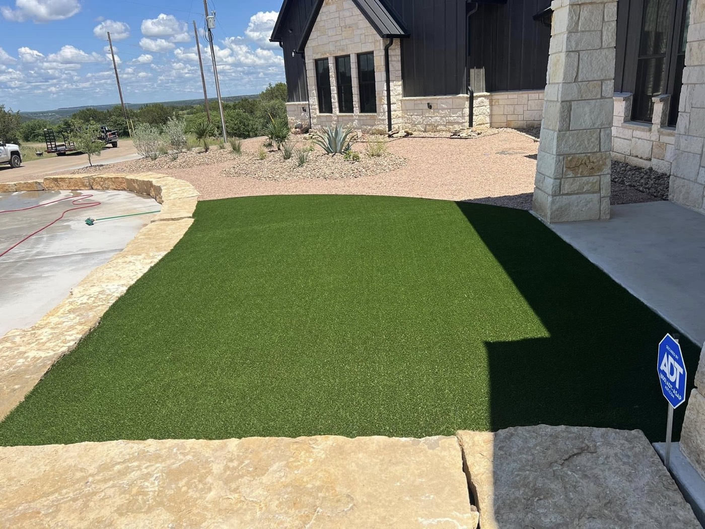 After: green turf, decorative rock and new plants beside the home