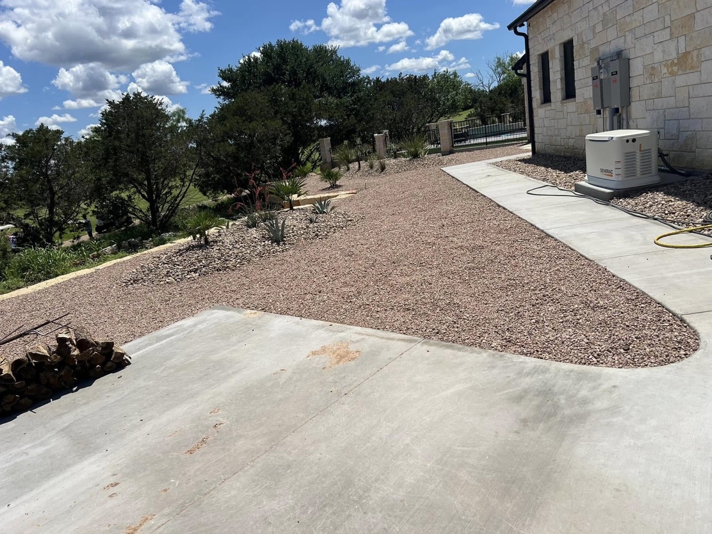 After: decorative rock beds and plants beside a finished driveway