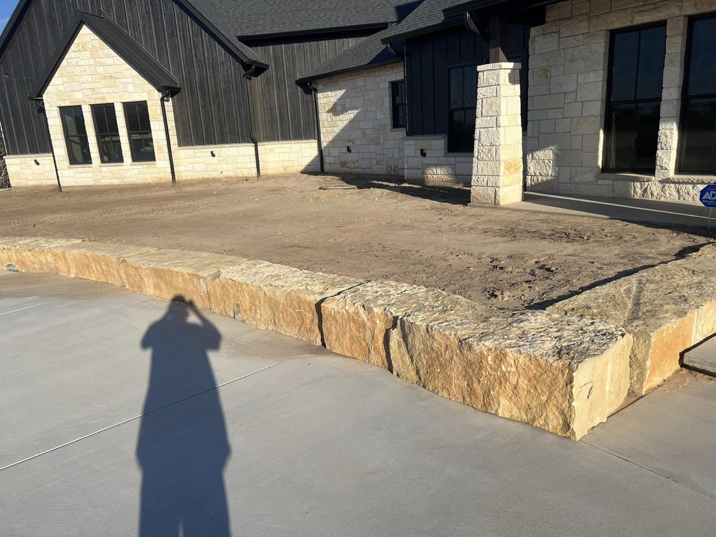 Before: bare planting beds and stone border beside a pool patio
