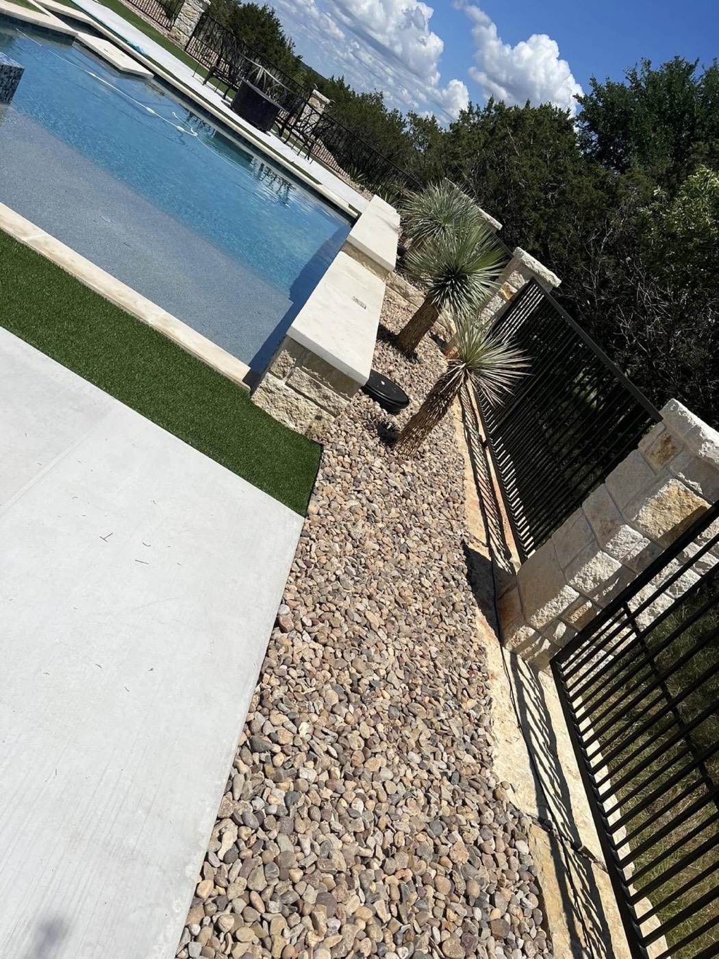 After: finished turf, decorative rock, and plants beside the pool