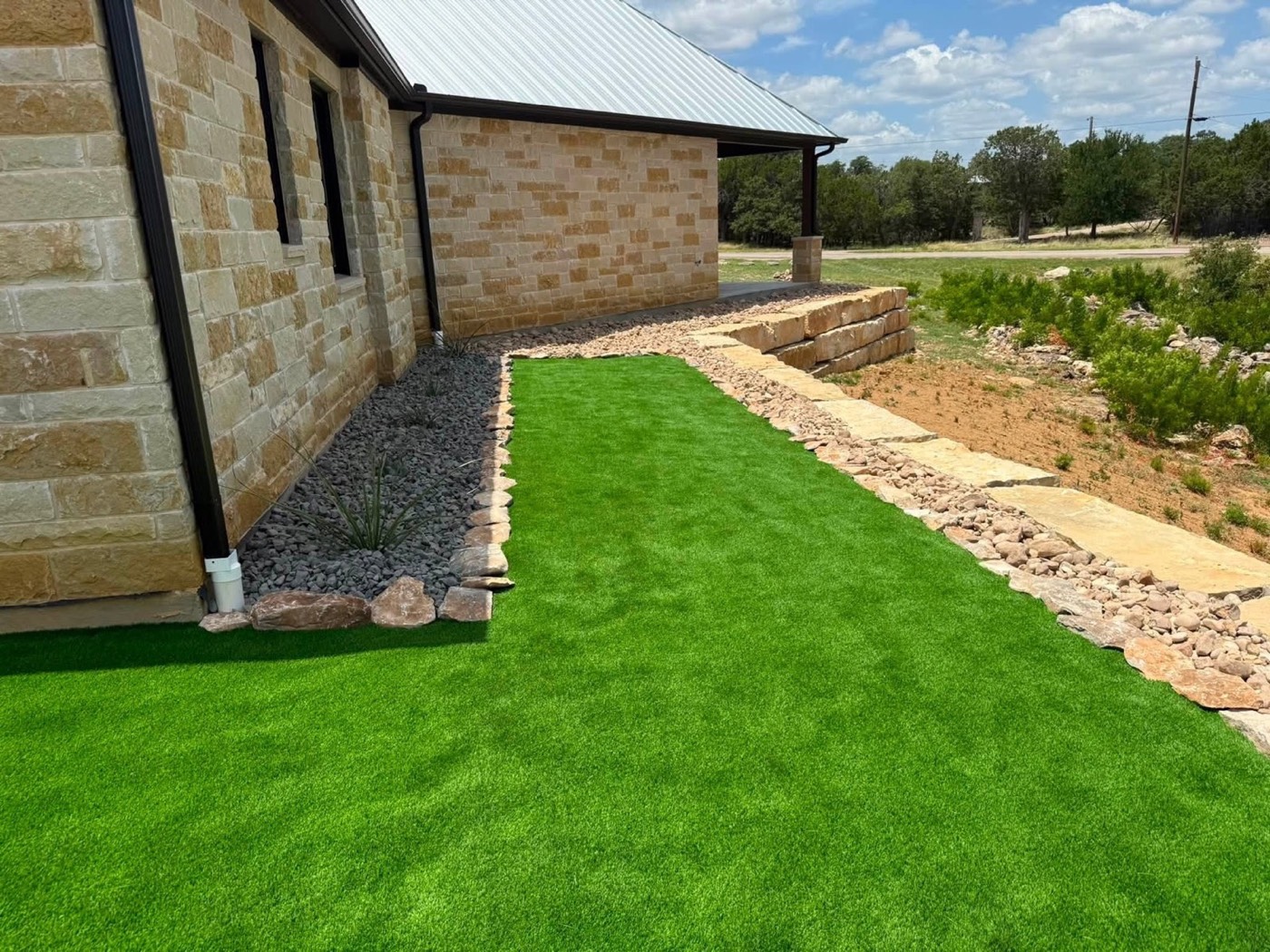 Turf and decorative rock beside a stone exterior