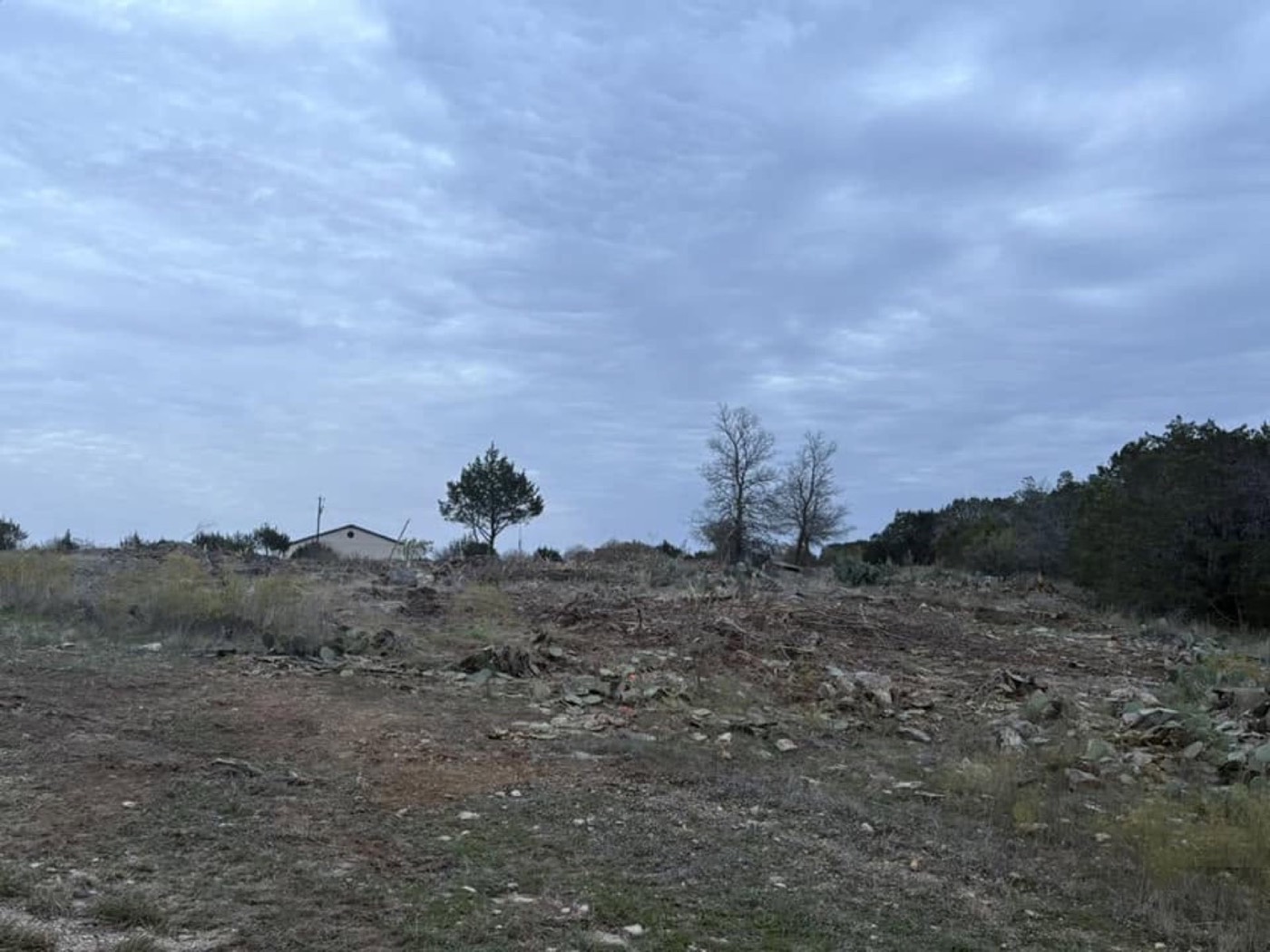 After: cleared and graded land with a gravel entrance