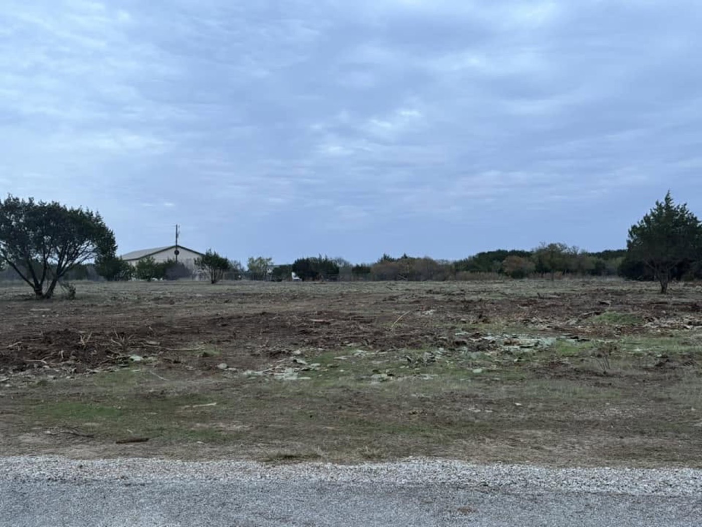 After: cleared and leveled roadside property with a gravel entrance